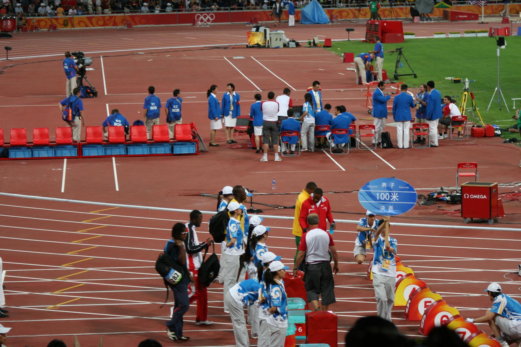 Officials and crew are gathered on the track preparing for the Men's 100m final at the Beijing 2008 Olympic Games.