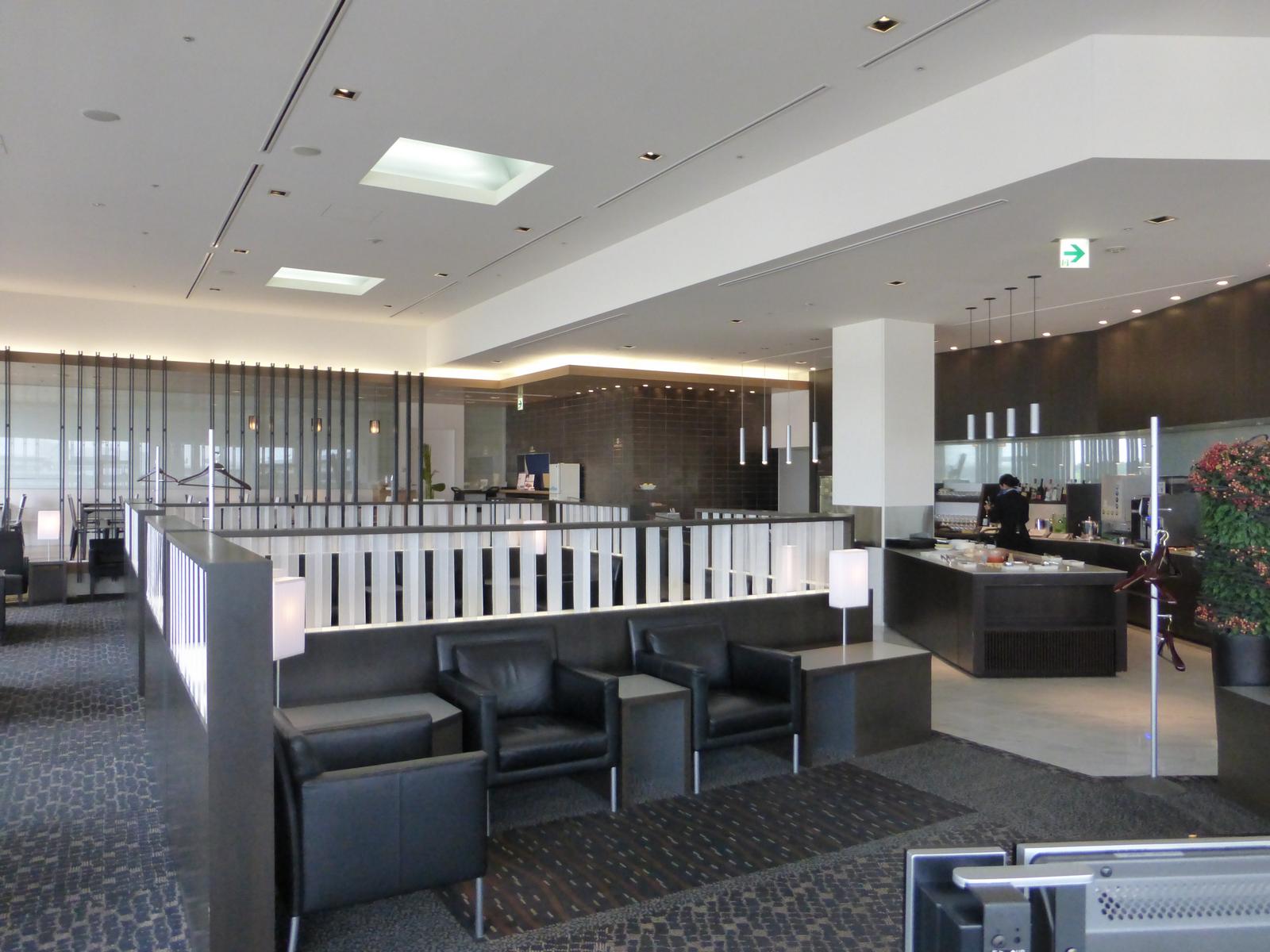 Interior view of the ANA First Class Lounge in Tokyo, showing comfortable seating areas and a food buffet.