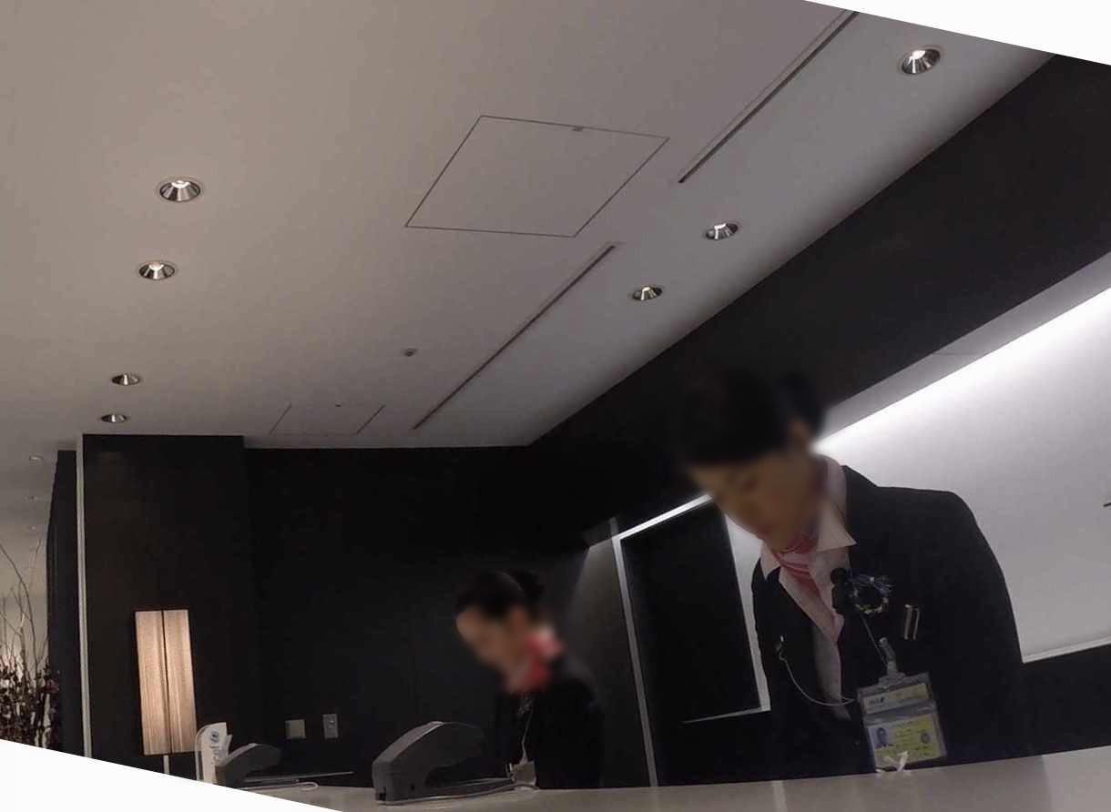 Two uniformed lounge staff members stand at a reception desk.