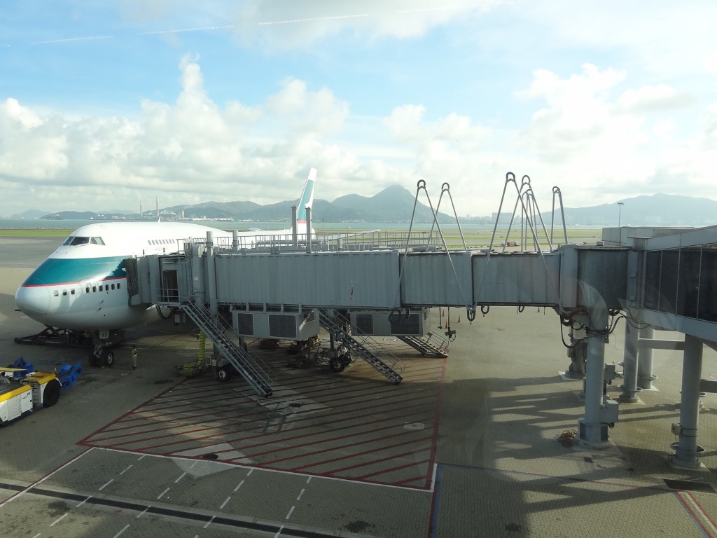 Cathay Pacific 747 aircraft at an airport gate, connected to a jet bridge.
