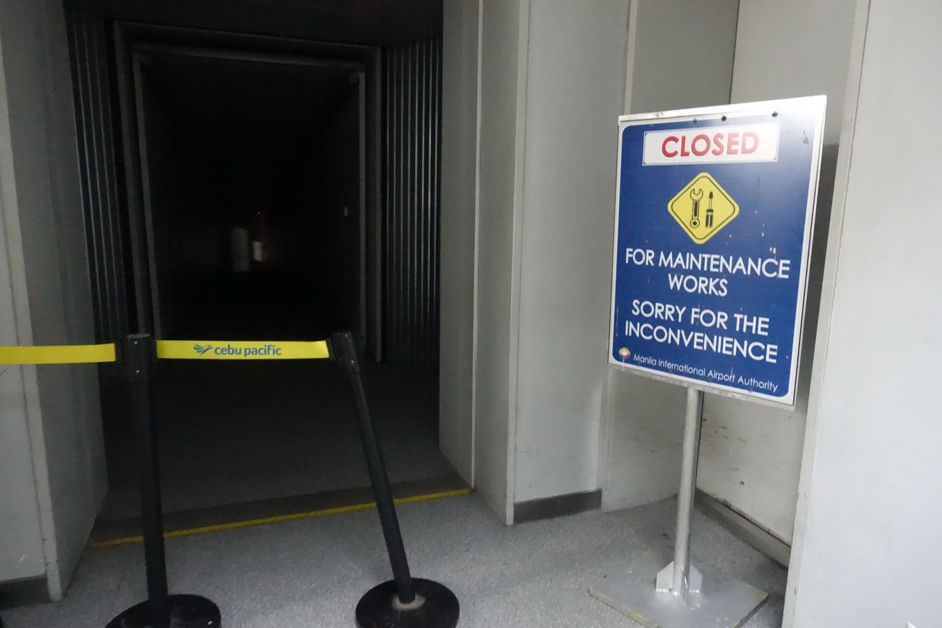 A "CLOSED FOR MAINTENANCE" sign and Cebu Pacific barrier block an airport gate.