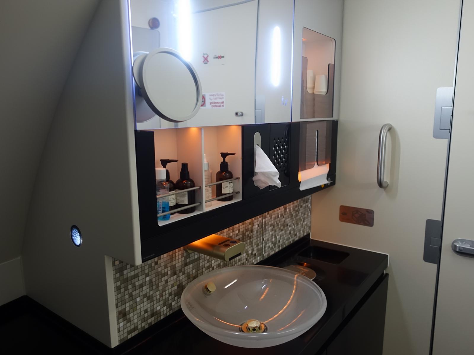 A luxurious lavatory in the Etihad A380 First Class cabin, featuring a modern sink, mirror, and premium toiletries.