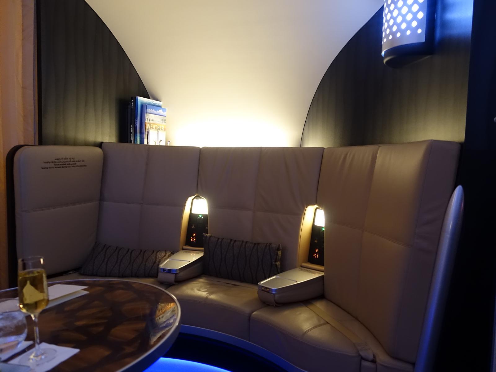 Curved lounge seating area with champagne on an Etihad A380 First Class flight.