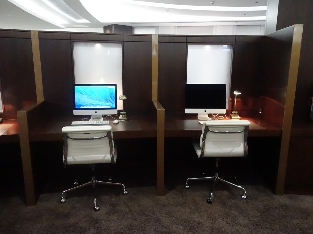 Two partitioned business cubicles each with an iMac computer and a white office chair.
