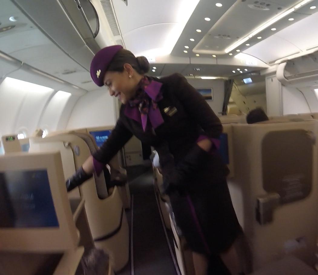 Etihad flight attendant smiling in the business class cabin.