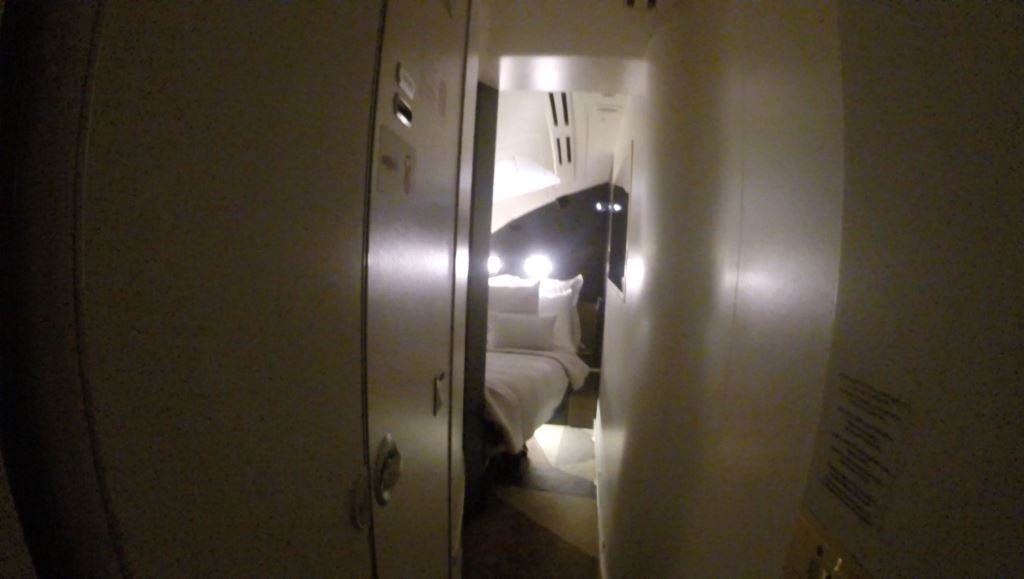Dimly lit view into the private bedroom of an Etihad A380 First Class Residence.