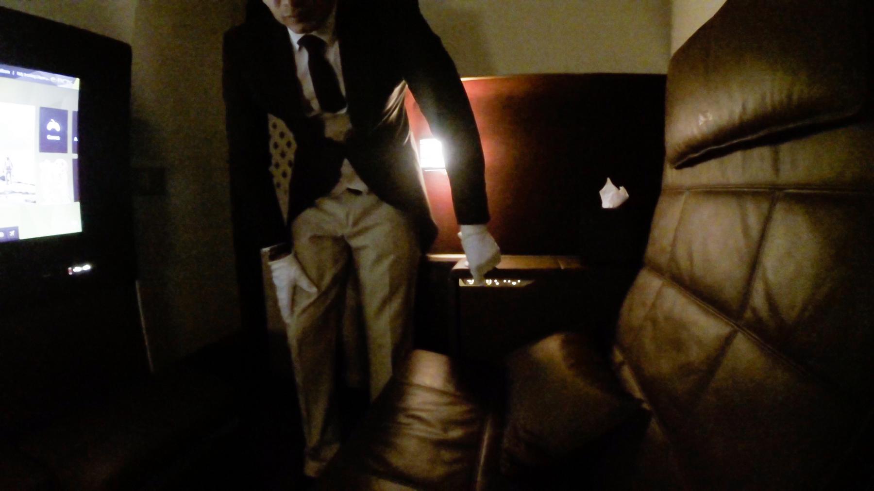 A butler in a suit and white gloves stands in a luxurious Etihad A380 First Class cabin.