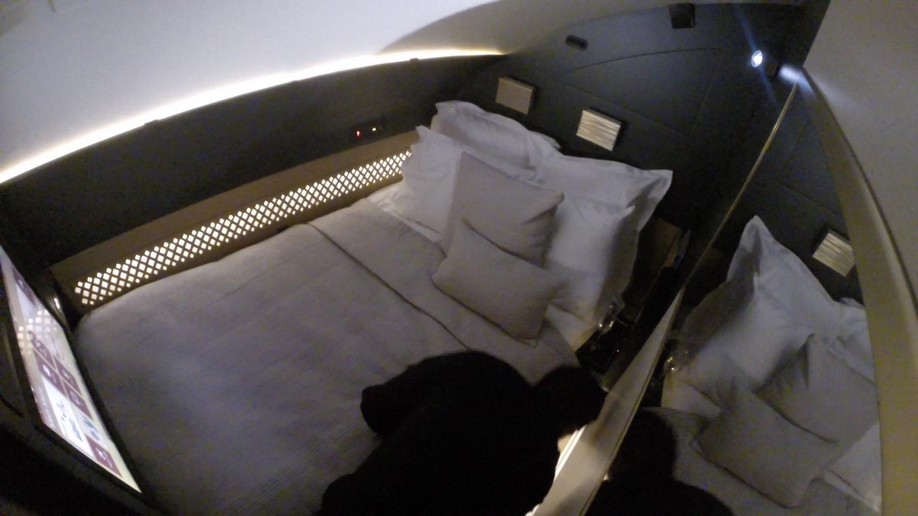 Luxurious private bed in an Etihad A380 First Class cabin with white bedding and ambient lighting.