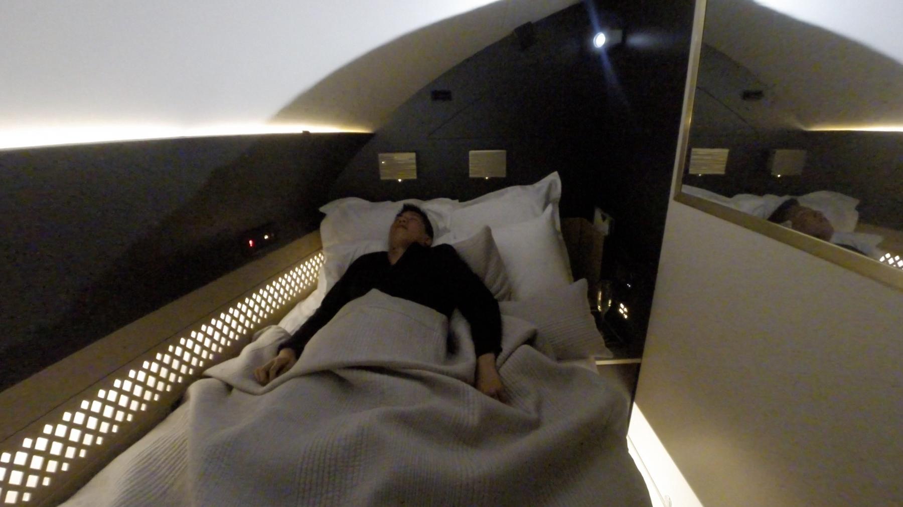 A person sleeps in the luxurious private bed of an Etihad A380 First Class suite.