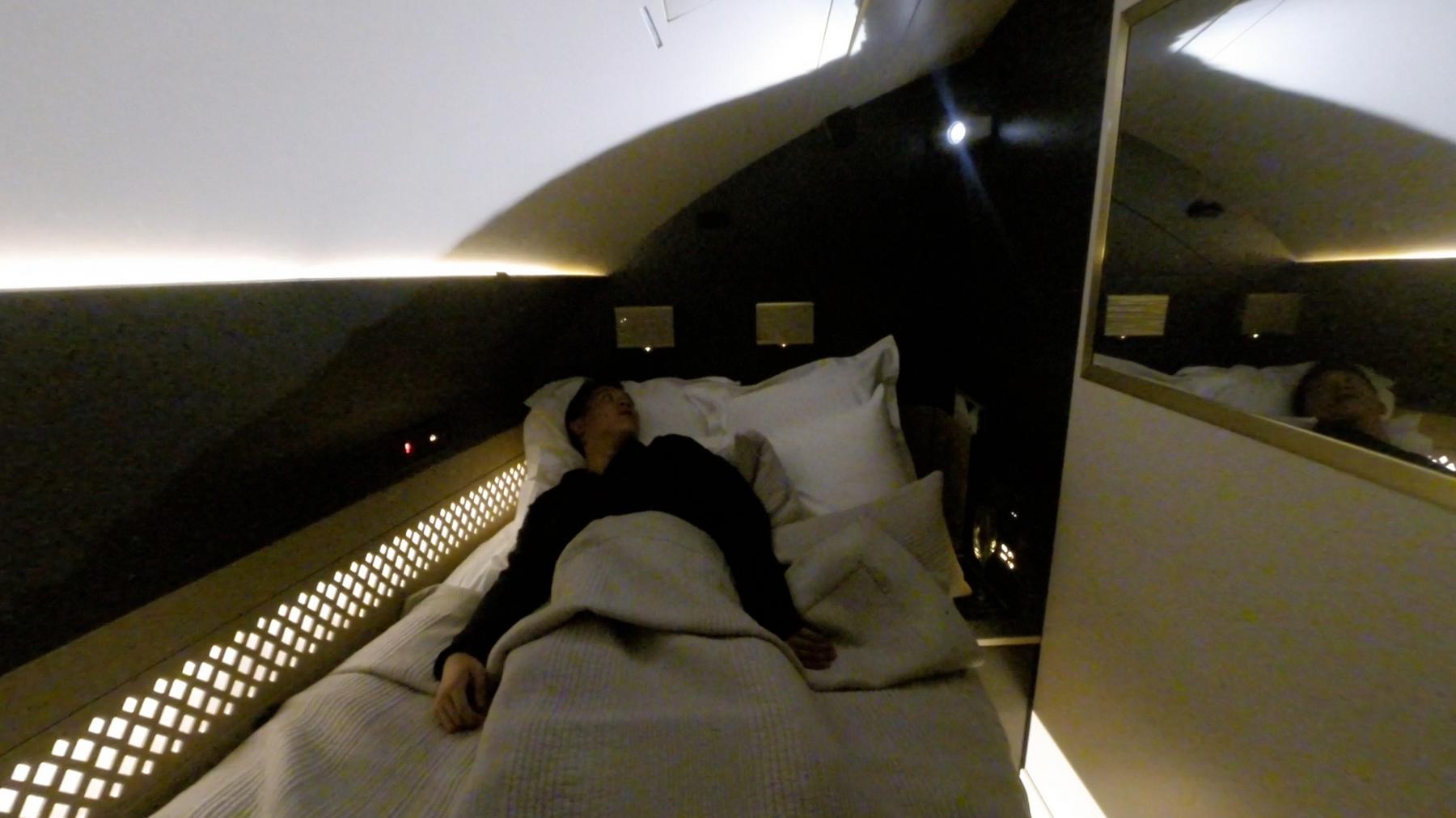 Man sleeping on a luxurious bed in Etihad A380 First Class.