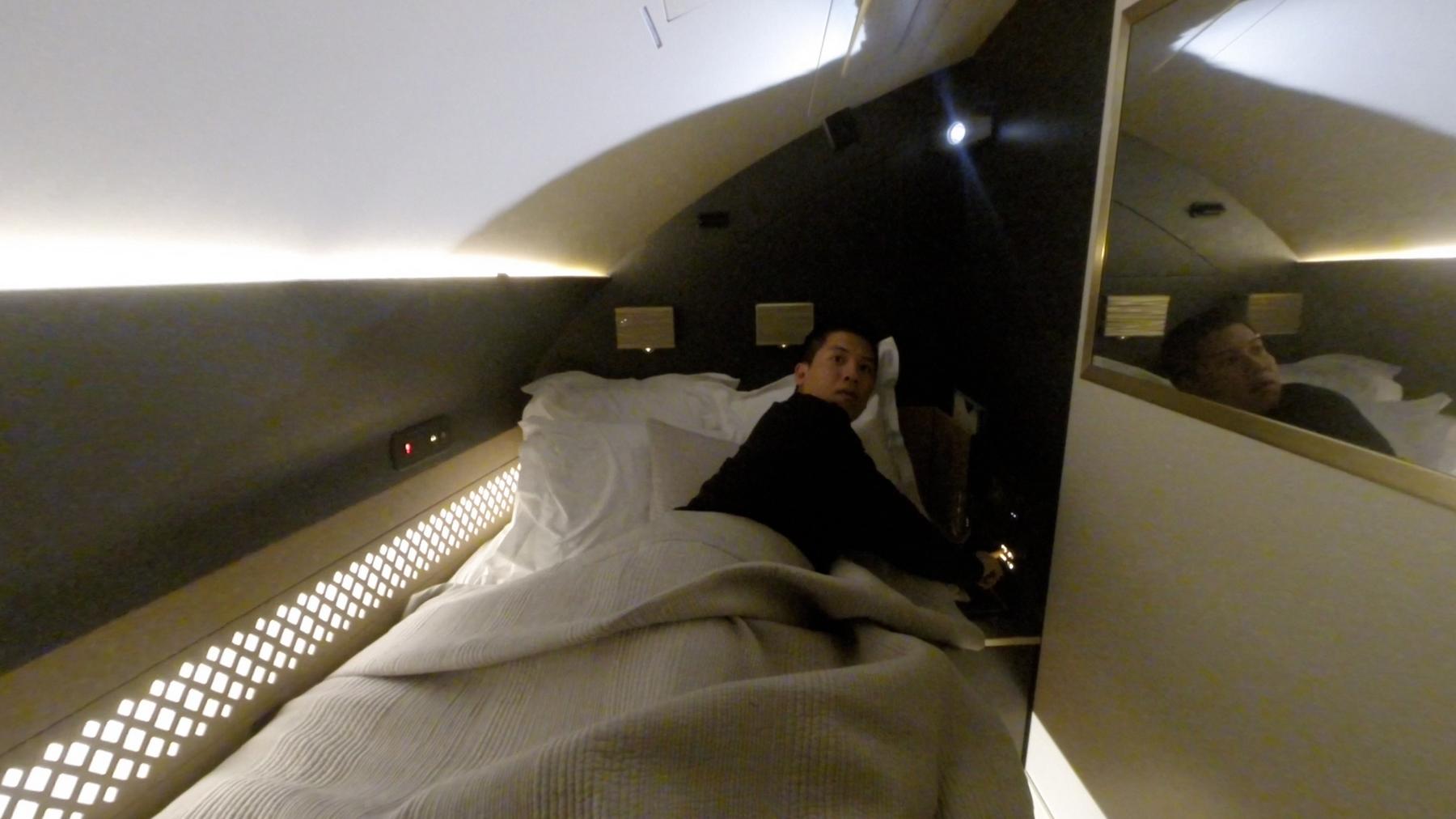 A man lies in a luxurious bed inside the Etihad A380 First Class cabin.