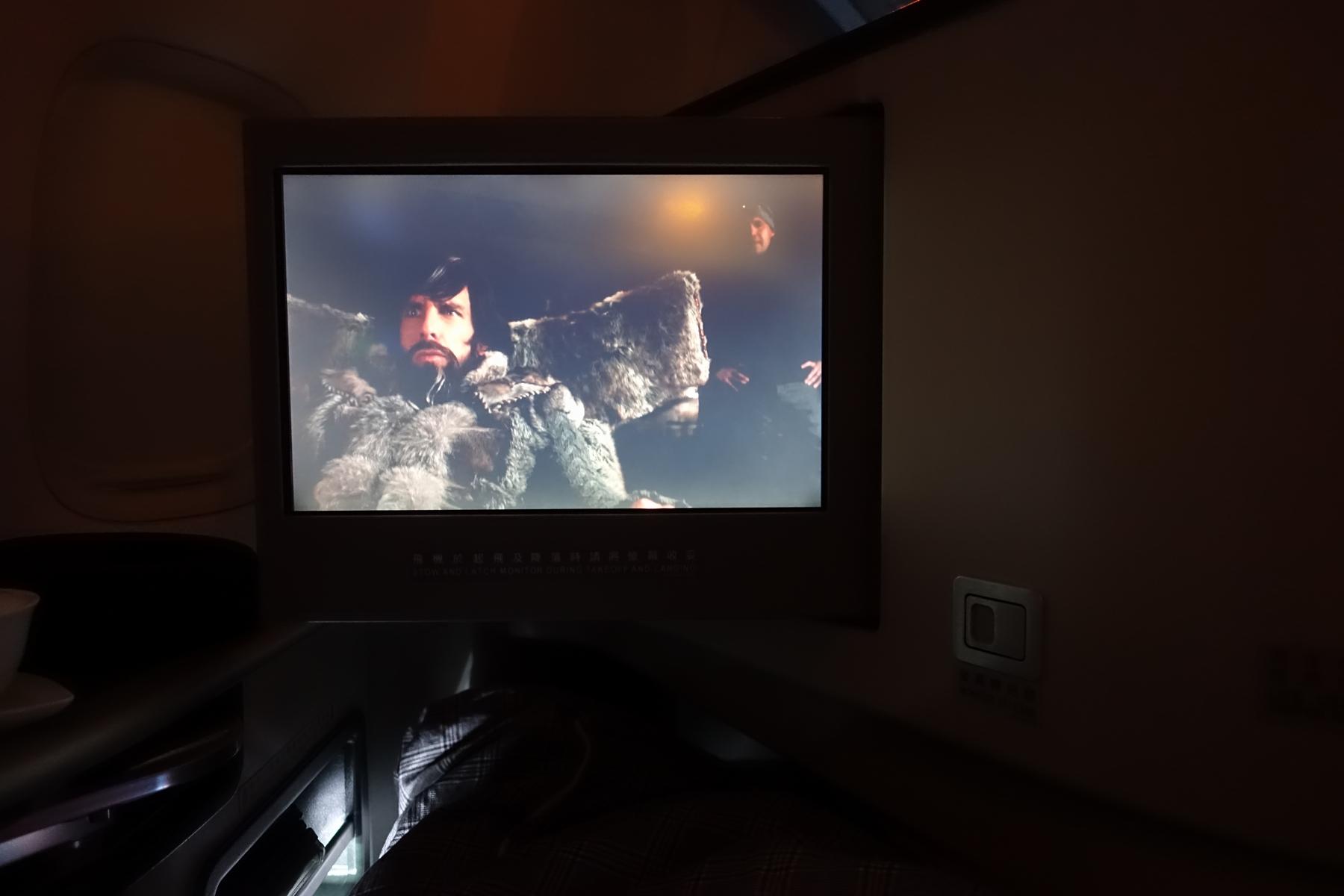 In-flight entertainment screen showing a movie in a dark Eva Air business class cabin.