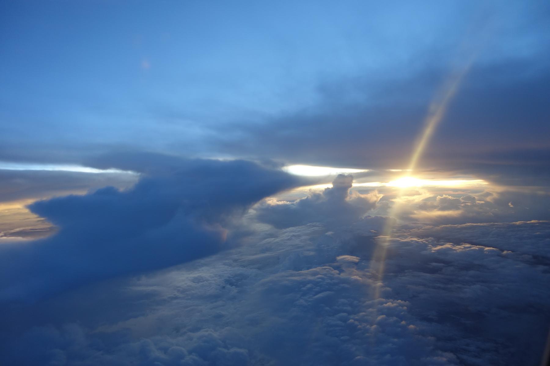Dramatic sunbeams pierce through thick clouds from an aerial perspective.