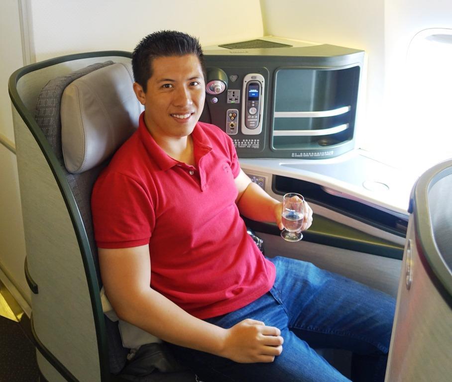 Man smiles in an Eva Air Royal Laurel Business Class seat, holding a glass.
