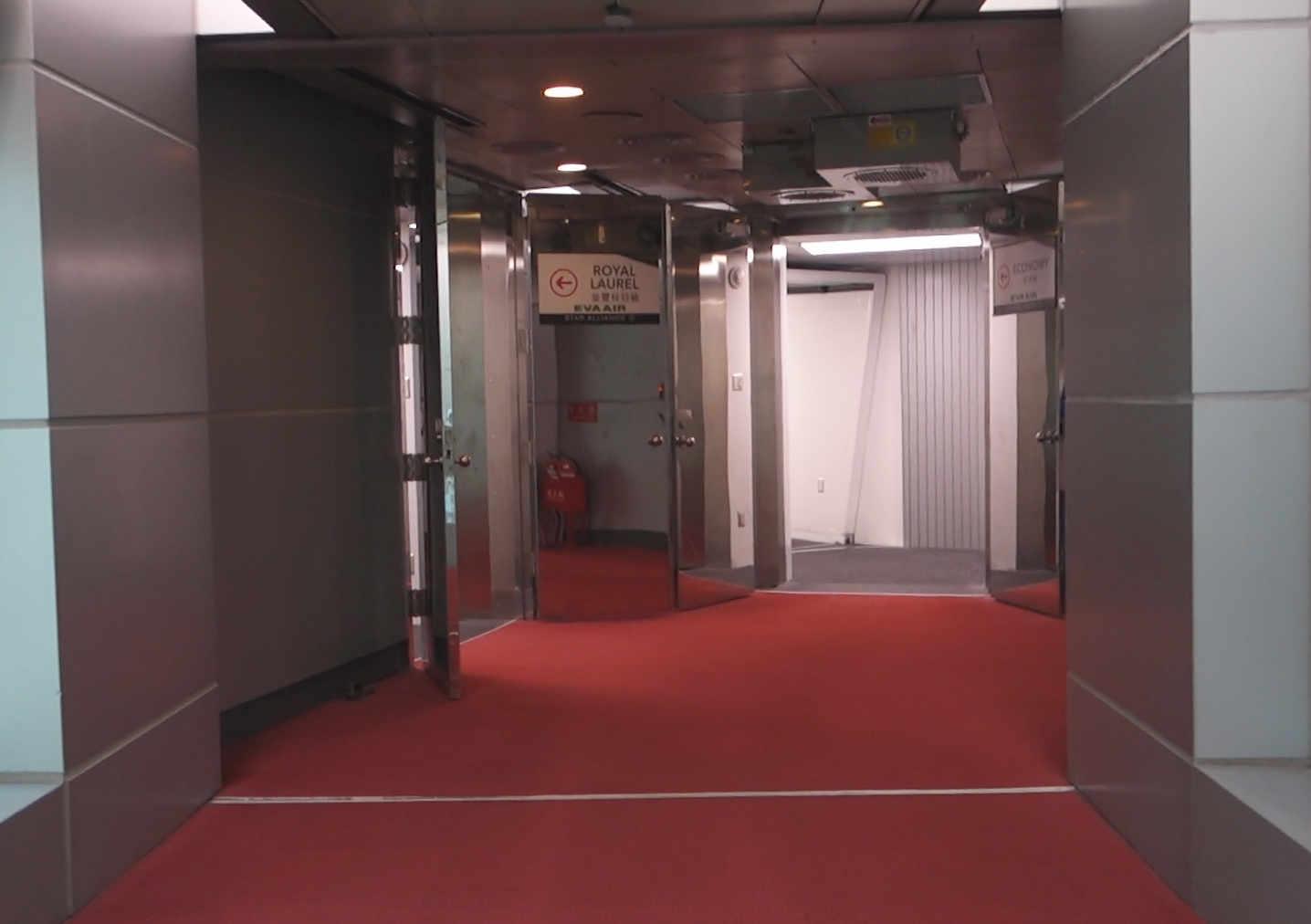 Red-carpeted airport hallway with signs for EVA Air's Royal Laurel and Economy class entrances.