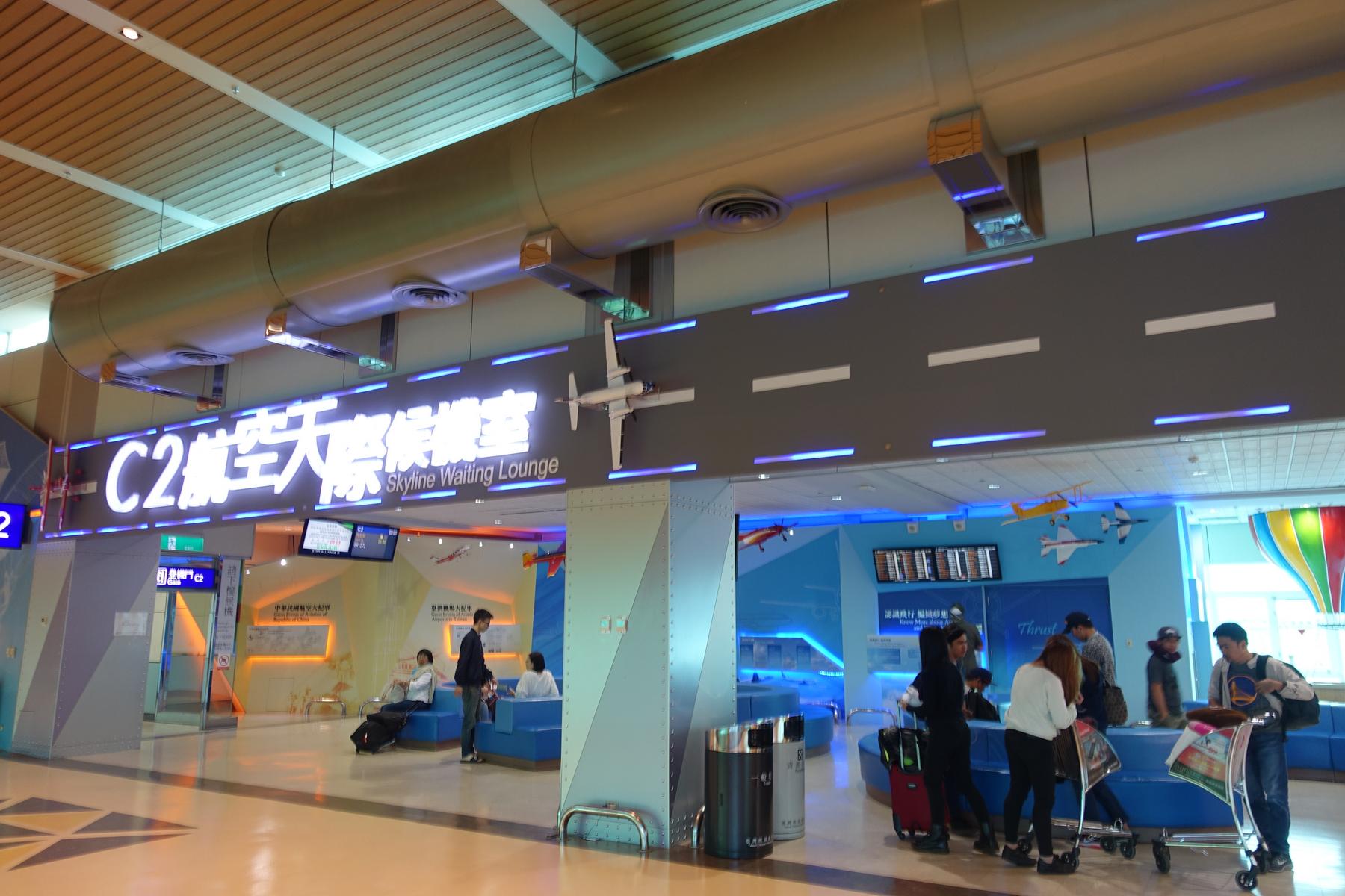 The C2 Skyline Waiting Lounge at Taipei airport with blue seating, airplane models, and glowing signs.