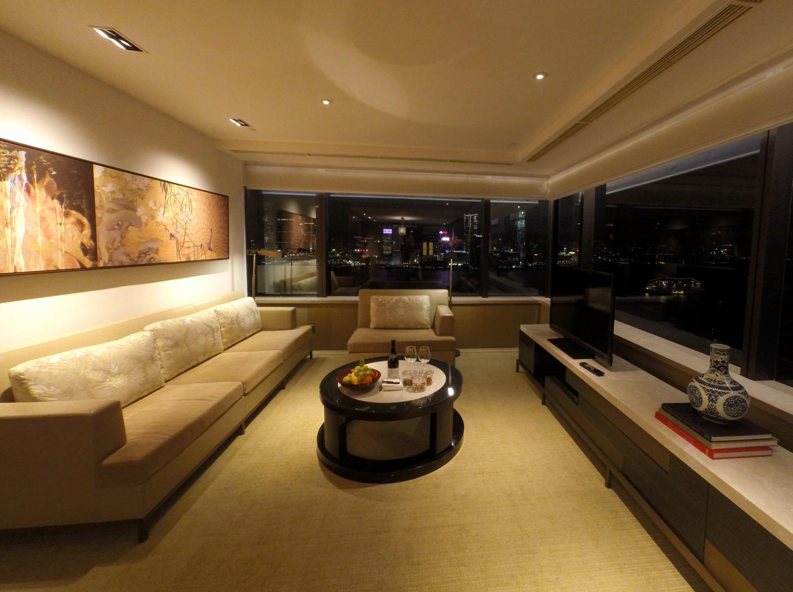 The Grand Suite living room at Grand Hyatt Hong Kong, featuring a long sofa, coffee table, and expansive night city views.
