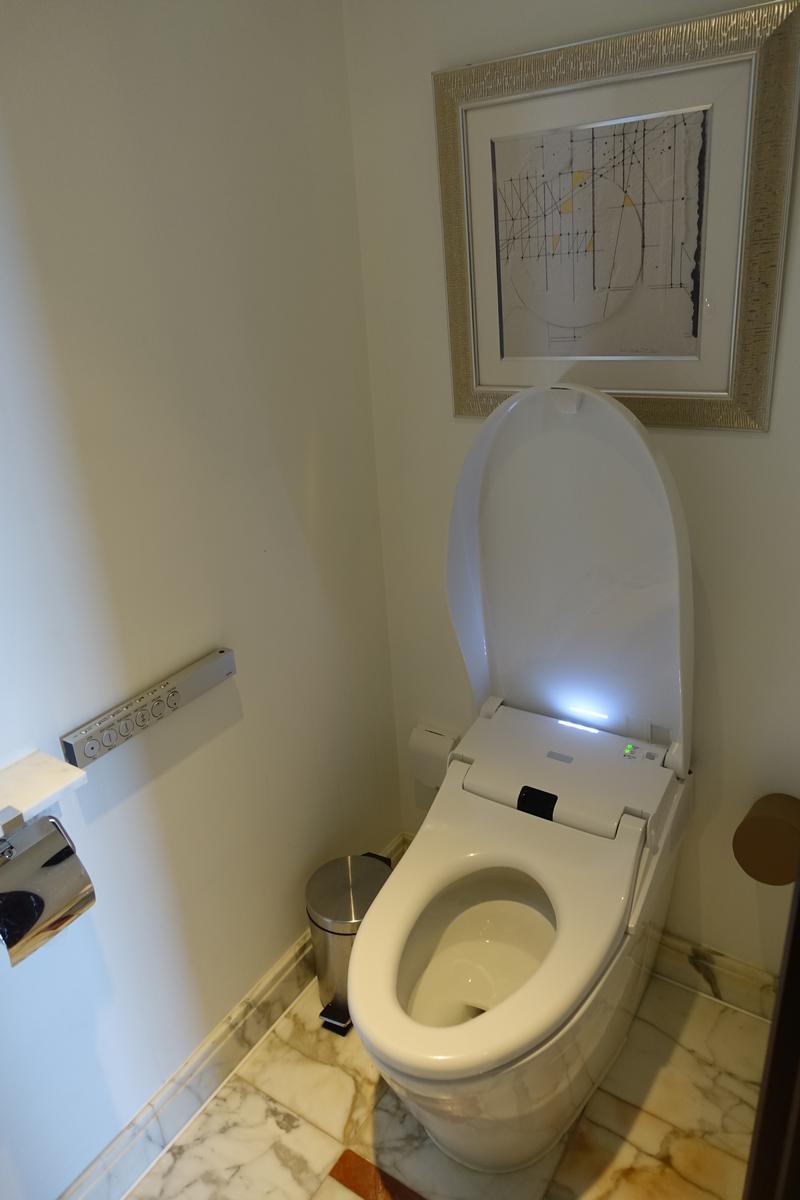 A high-tech bidet toilet with its lid open in a modern hotel bathroom.