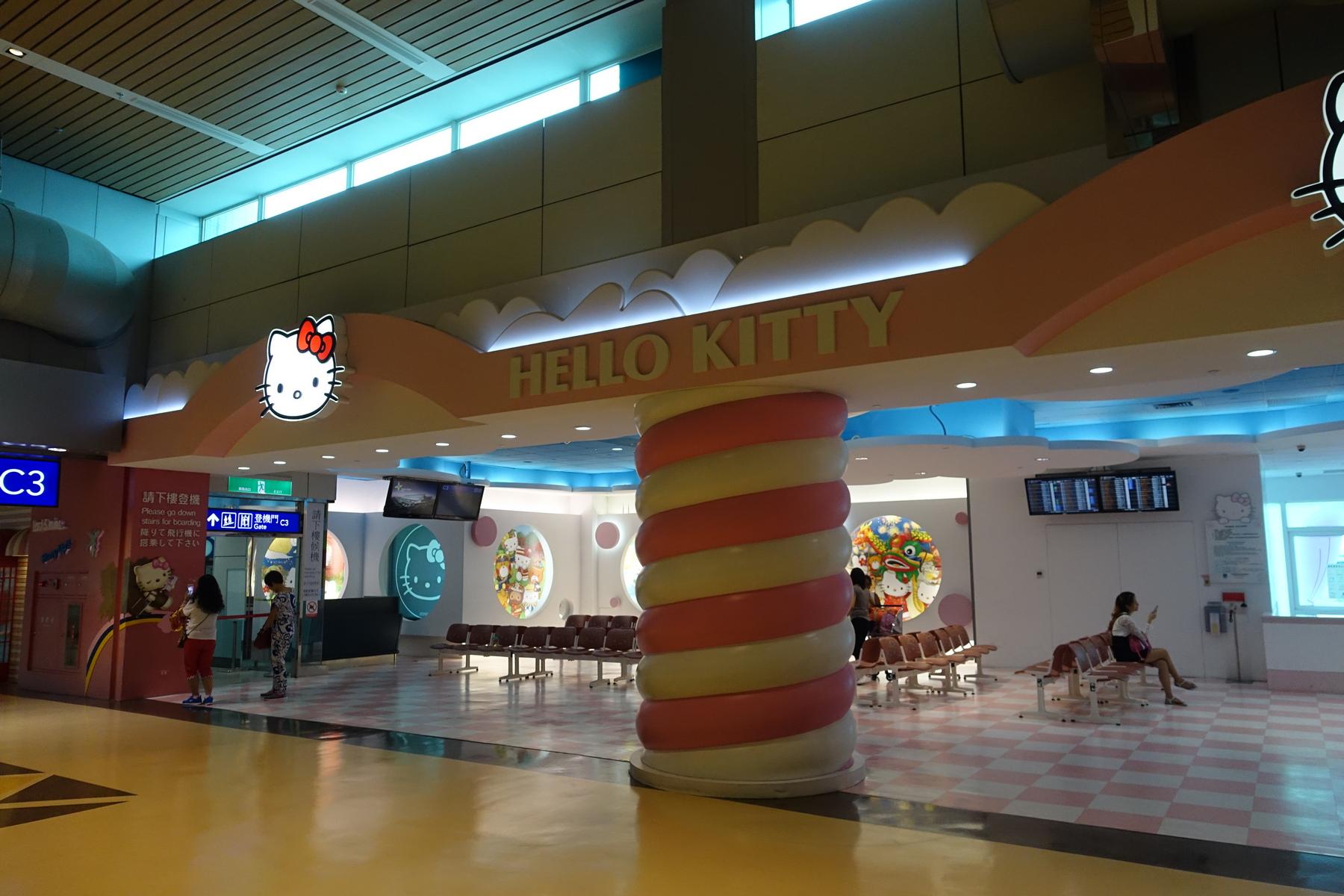 A colorful Hello Kitty themed airport lounge, featuring a pink and white checkerboard floor and a large candy-striped column.