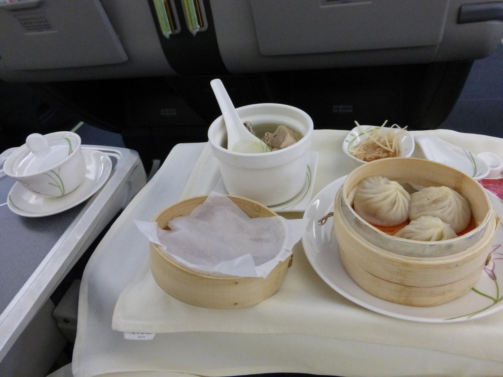 An in-flight business class meal featuring soup dumplings, soup, and shredded ginger.