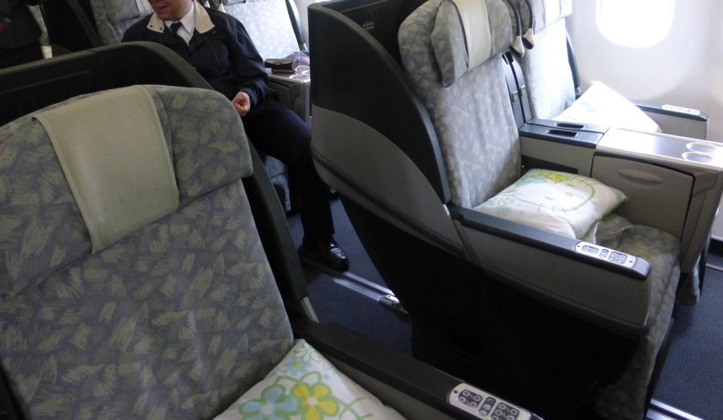 Eva Air Business Class cabin with grey patterned seats, one featuring a Hello Kitty pillow.
