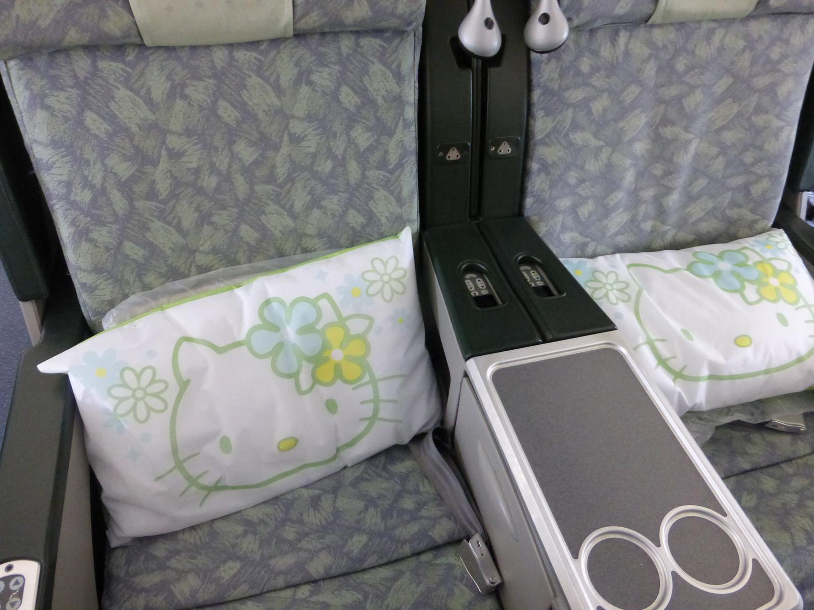 Two Eva Air Premium Laurel Class airplane seats, each with a Hello Kitty pillow.