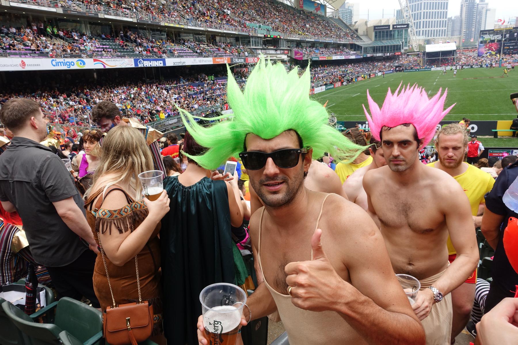 A man in a spiky green wig and sunglasses gives a thumbs up at the Hong Kong Rugby Sevens.