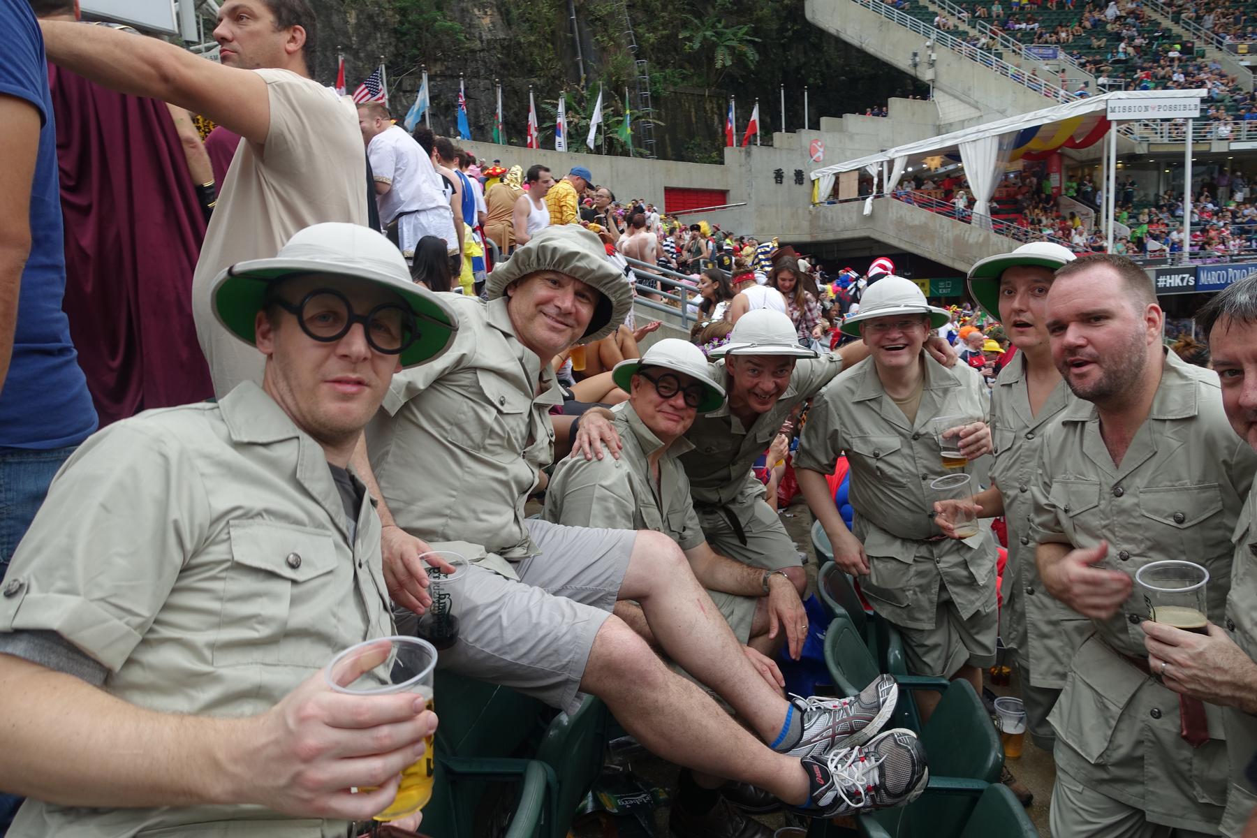 A group of men in safari costumes drink beer and smile at the Hong Kong Rugby Sevens South Stand.