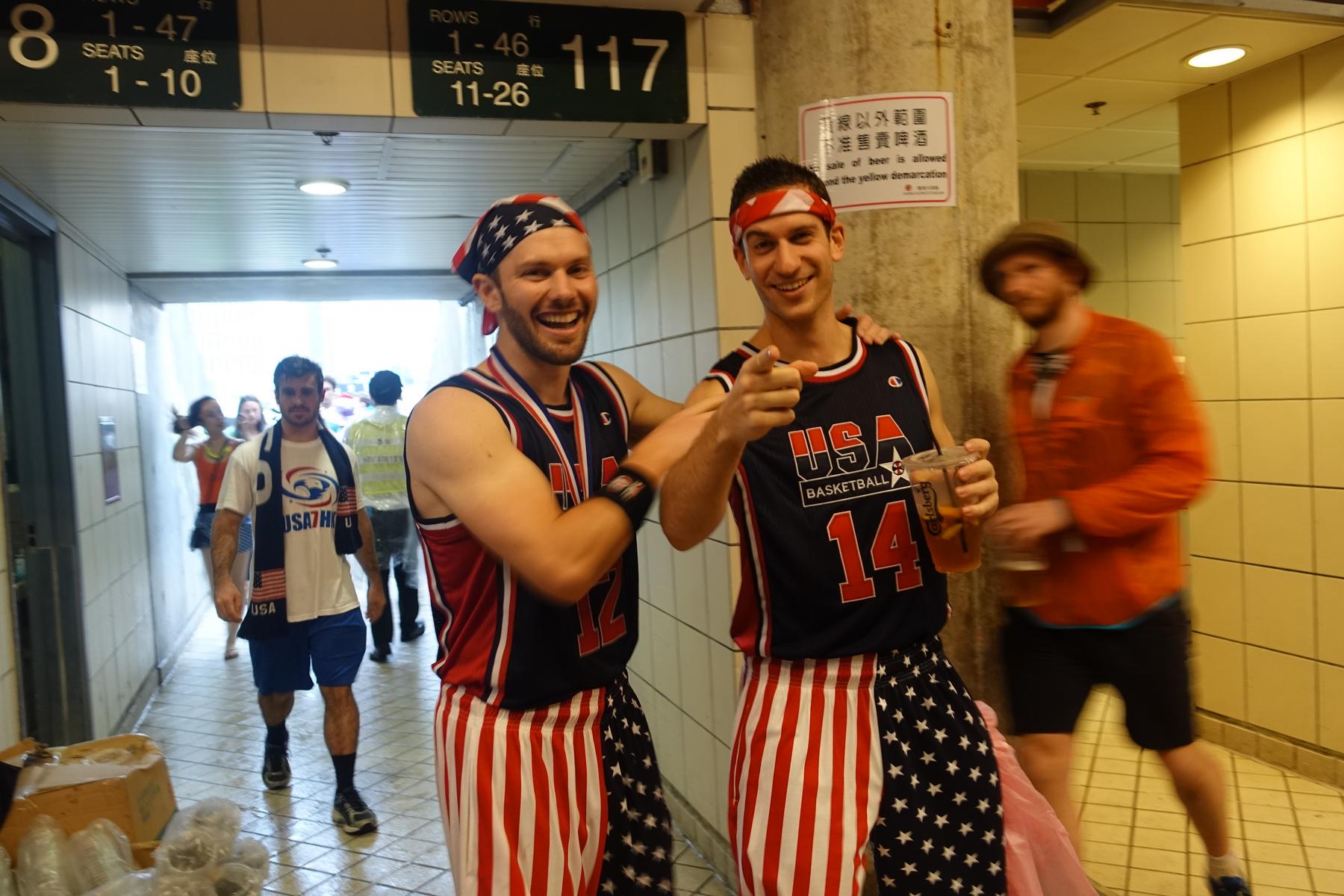 Two celebrating fans in American flag-themed outfits pose in a stadium concourse at the Hong Kong Rugby Sevens.