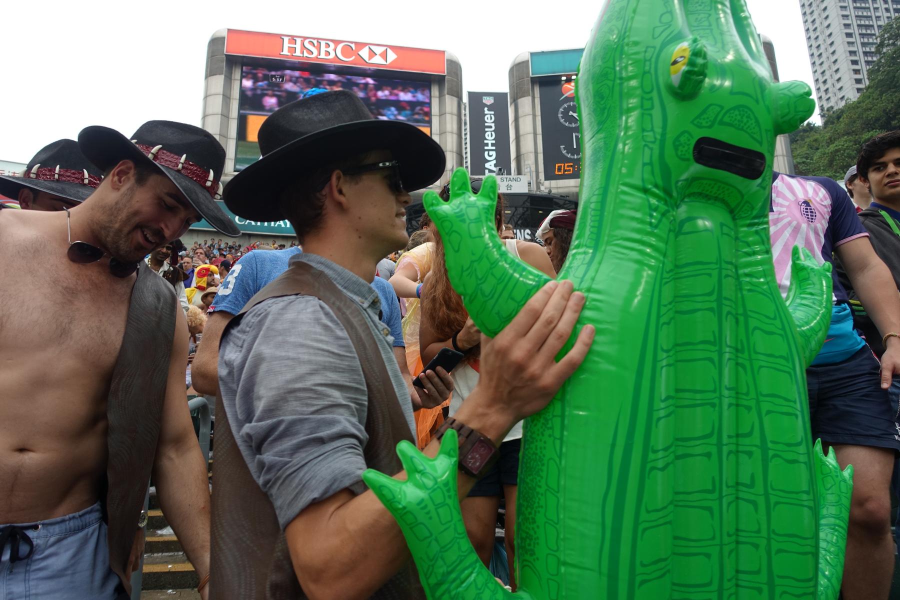 Costumed fans, including cowboys and an inflatable alligator, enjoy the atmosphere at the Hong Kong Rugby Sevens.