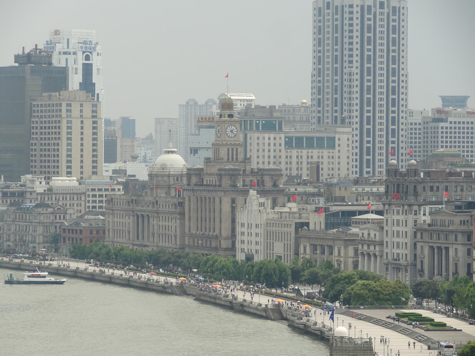 Panoramic view of Shanghai's Bund featuring the Huangpu River, historic European-style buildings, and modern skyscrapers.