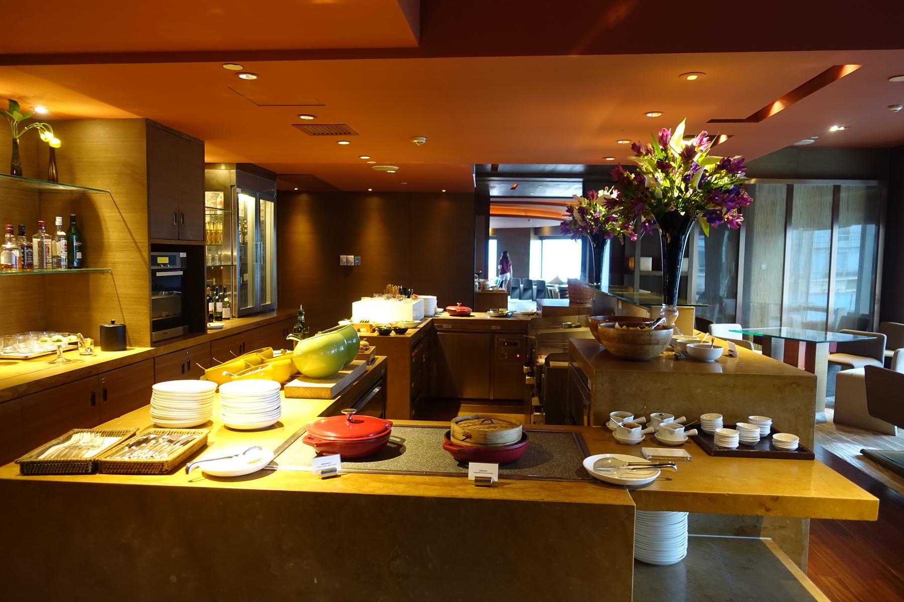 A club lounge buffet area featuring food, drinks, and elegant floral decorations.