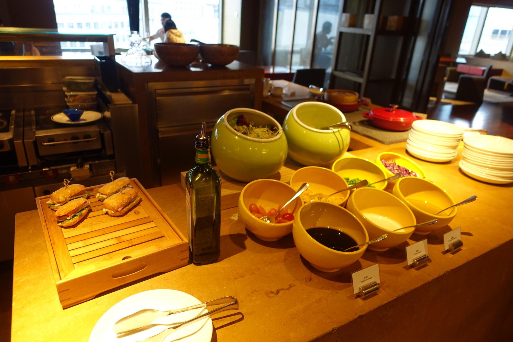 A hotel club lounge buffet features small sandwiches, a salad bar, and various dressings.