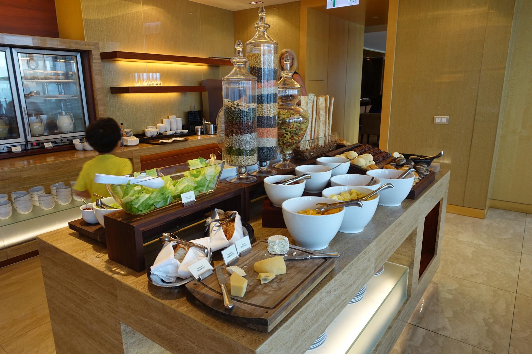 A hotel breakfast buffet station featuring salads, layered grains, breads, cheeses, and other dishes.