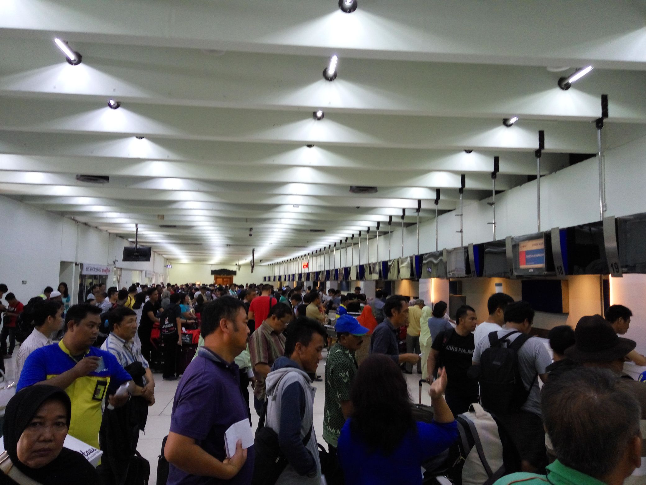 Crowded airport check-in area with passengers waiting in lines.