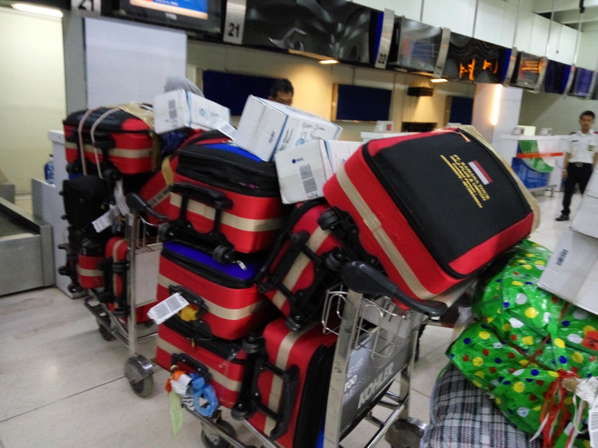 Several airport luggage carts piled high with red suitcases, boxes, and other bags.