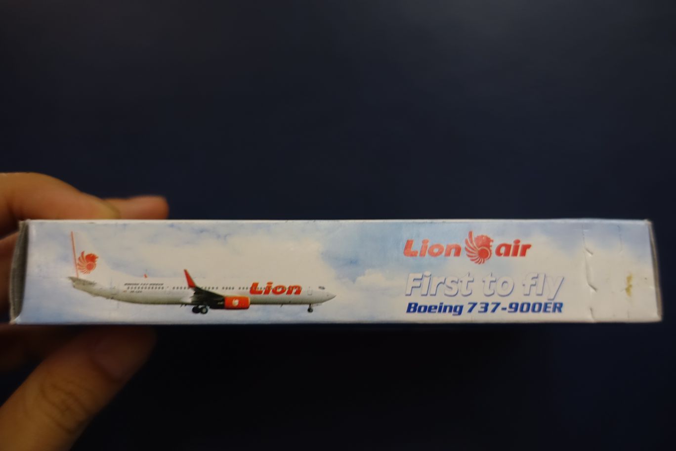 A hand holds a box featuring a Lion Air Boeing 737-900ER airplane.