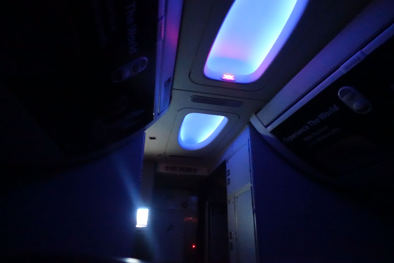 Airplane cabin interior with blue and purple ambient lighting.