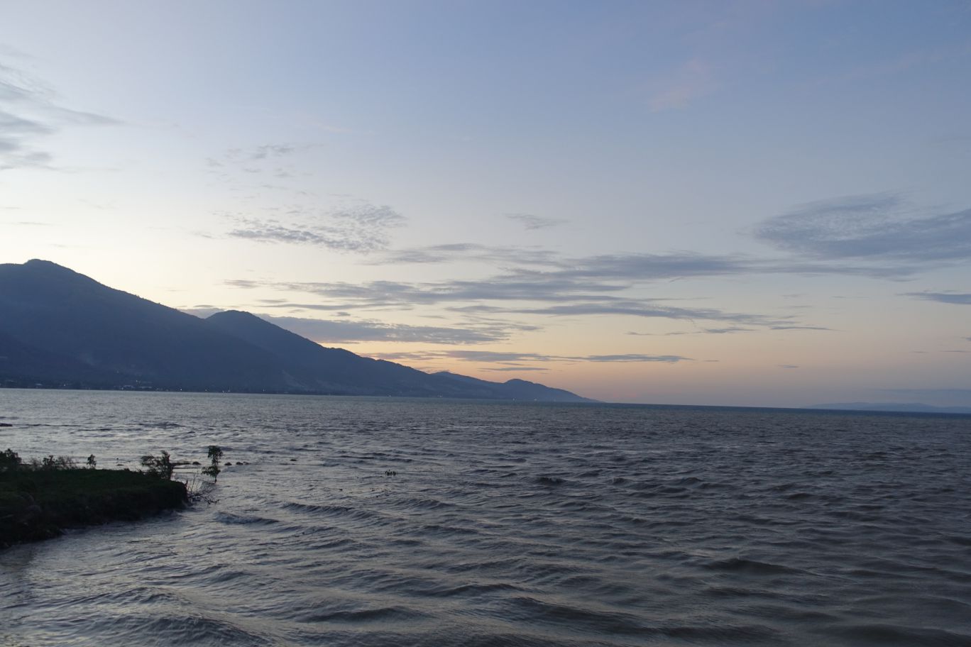 View of Palalu Bay with distant mountains under a twilight sky.