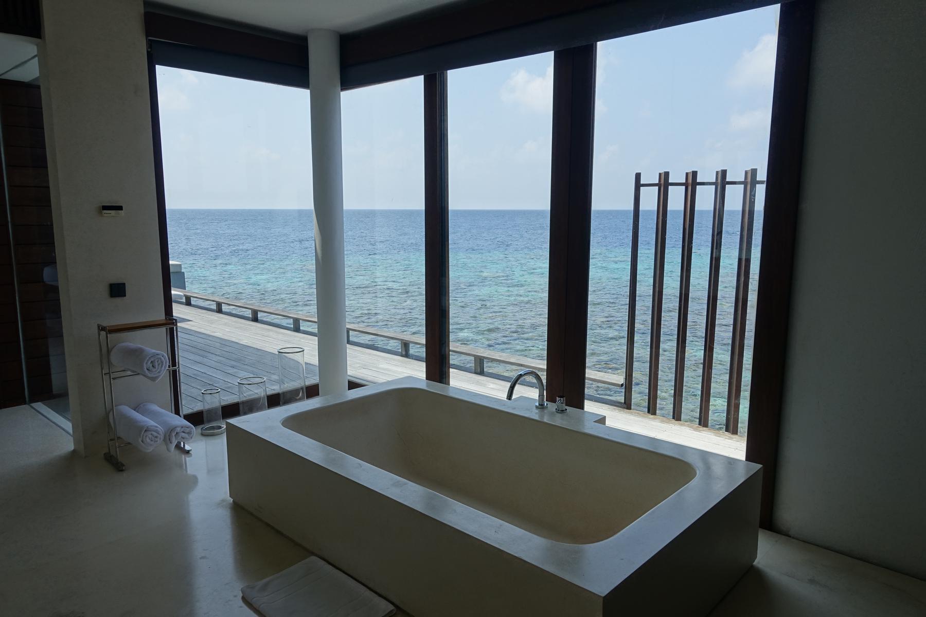Bathtub in a water villa bathroom with a panoramic ocean view.