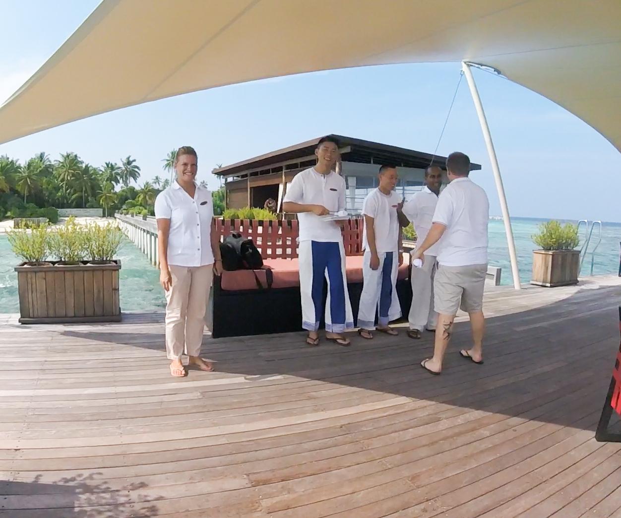 Hotel staff stand on an overwater wooden deck at the Park Hyatt Maldives.
