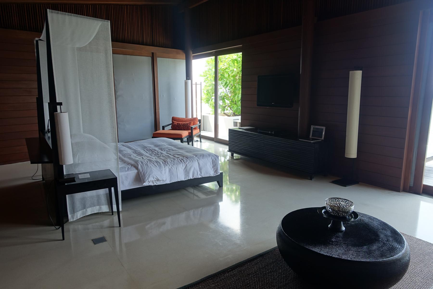 Modern bedroom of a Park Hyatt Maldives water villa with a bed, television, and lush outdoor view.