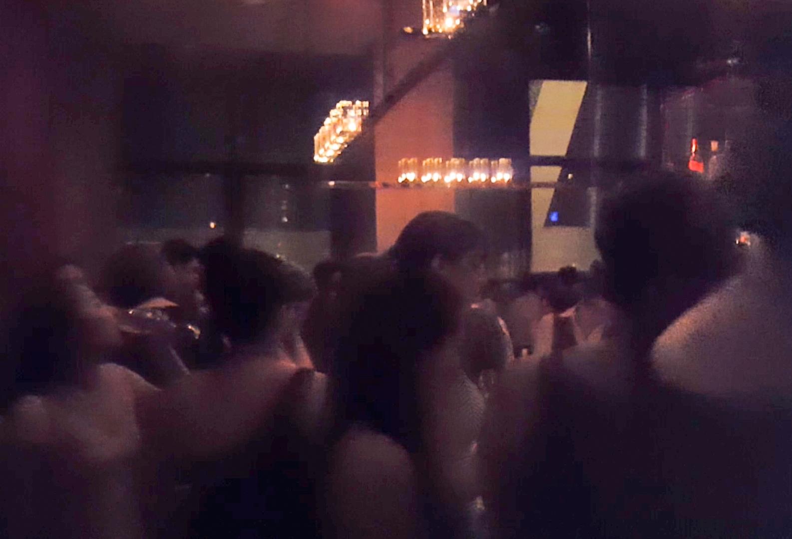 A blurry photo of a crowded happy hour bar, dimly lit with warm decorative lights.