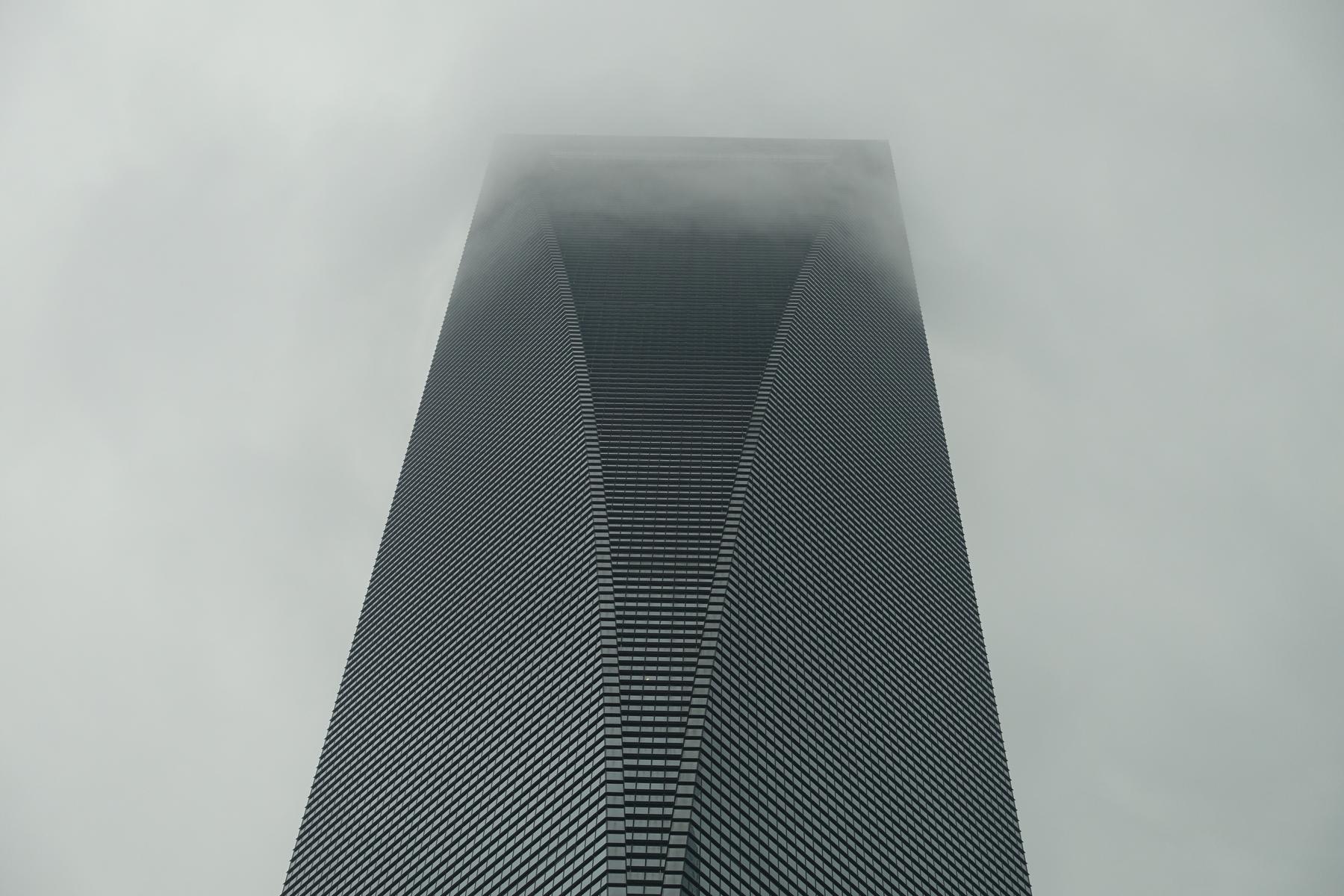 The Shanghai World Financial Center skyscraper's top disappears into thick fog.