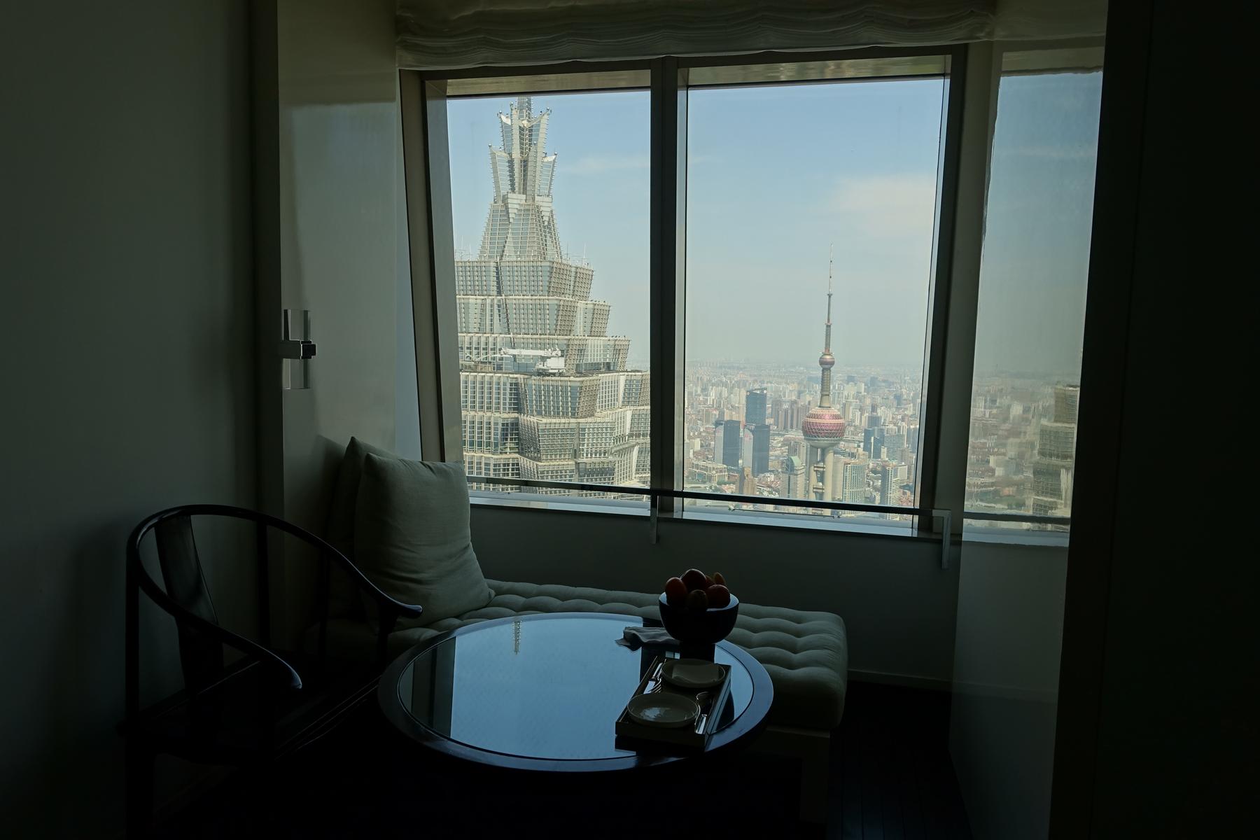 A hotel suite's lounge area with a window view of Shanghai's Jin Mao Tower and Oriental Pearl TV Tower.