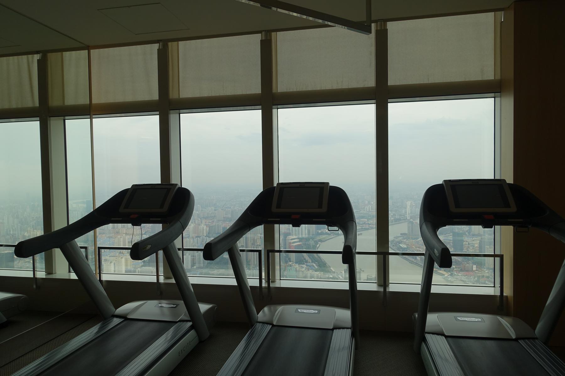 Three treadmills in a high-rise gym offering a panoramic view of Shanghai.