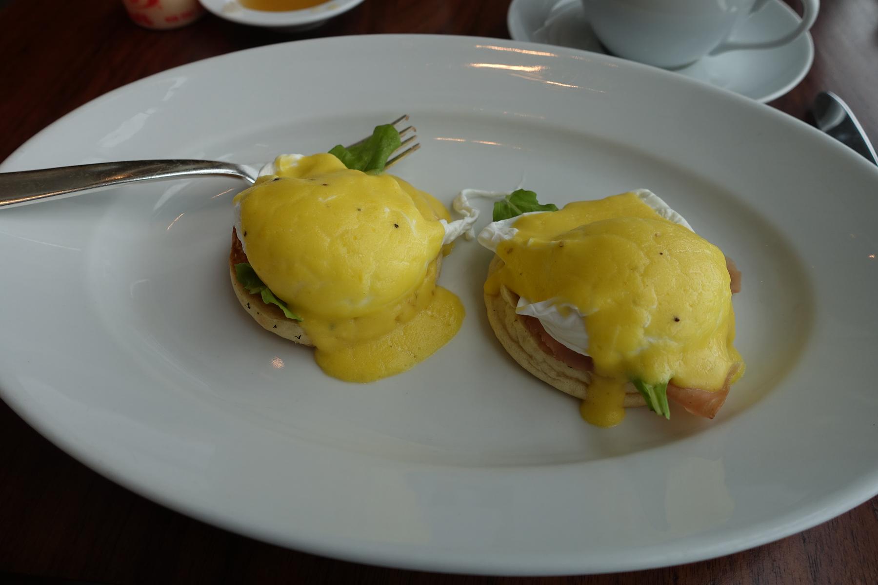 Two servings of eggs Benedict with hollandaise sauce on a white plate.