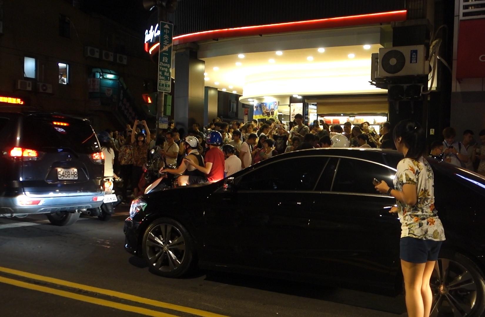 A large crowd of people, many holding phones, fill a Taiwan street at night during a Pokemon Go stampede.