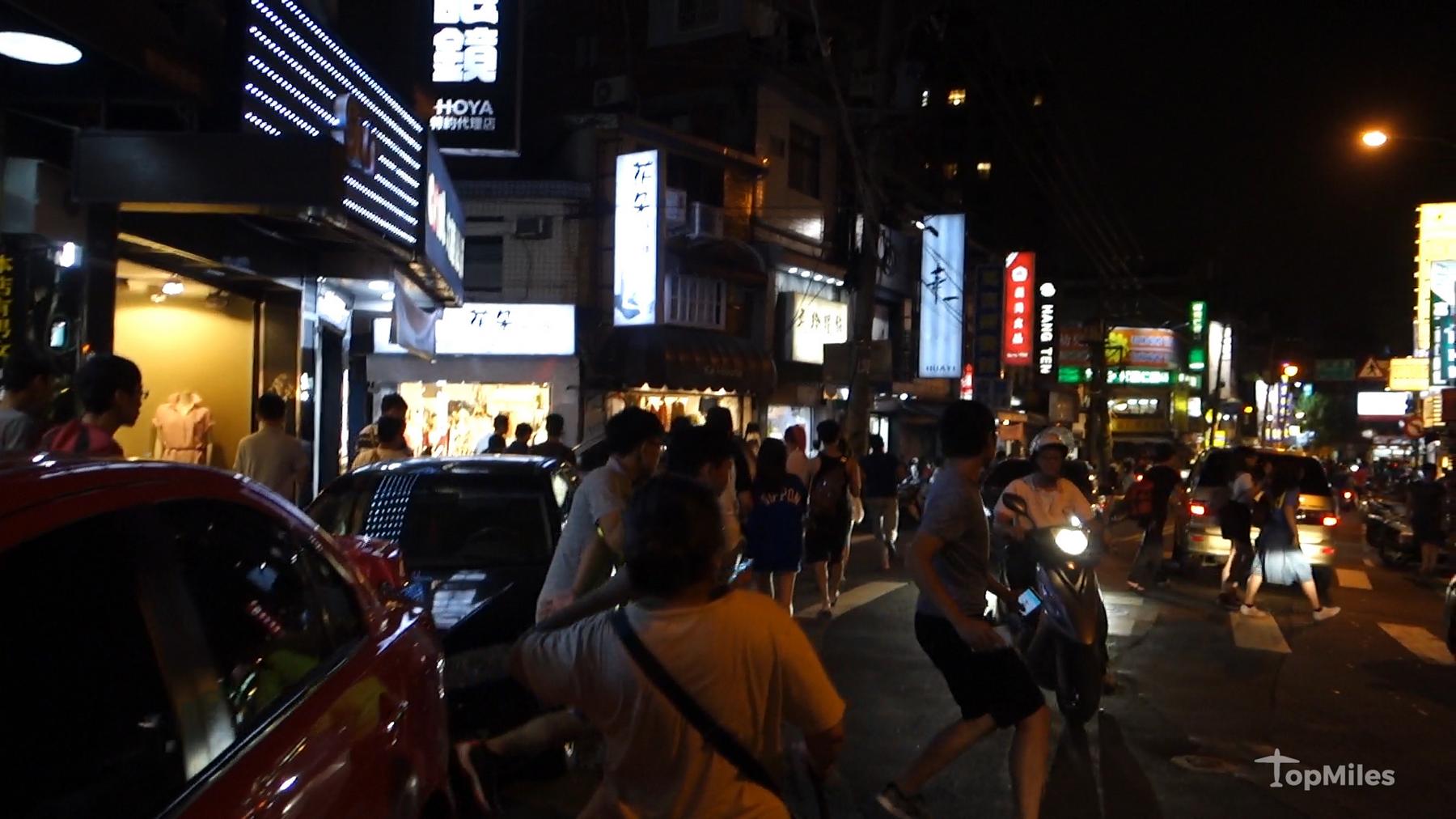 A crowded street at night in Taiwan with people running and walking, consistent with a Pokemon Go stampede.
