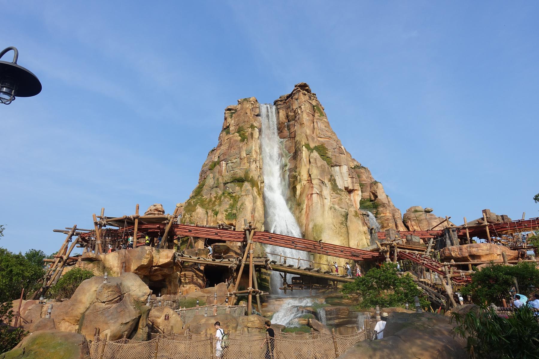A large rock mountain with a waterfall and wooden bridges winding through it at Shanghai Disneyland.